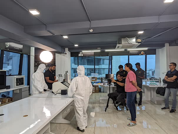 Filming technicians in white suits inside a laboratory