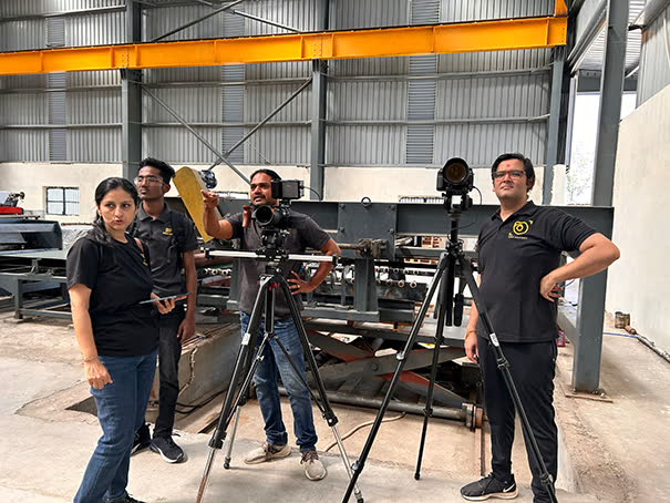 Camera on tripods filming a crew in an industrial shed