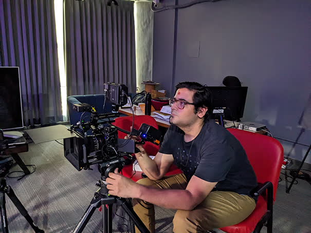 Camera operator framing an interview in a red chair